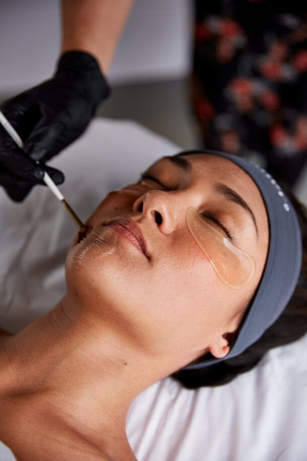 Woman having a chemical peel applied to her face with a brush